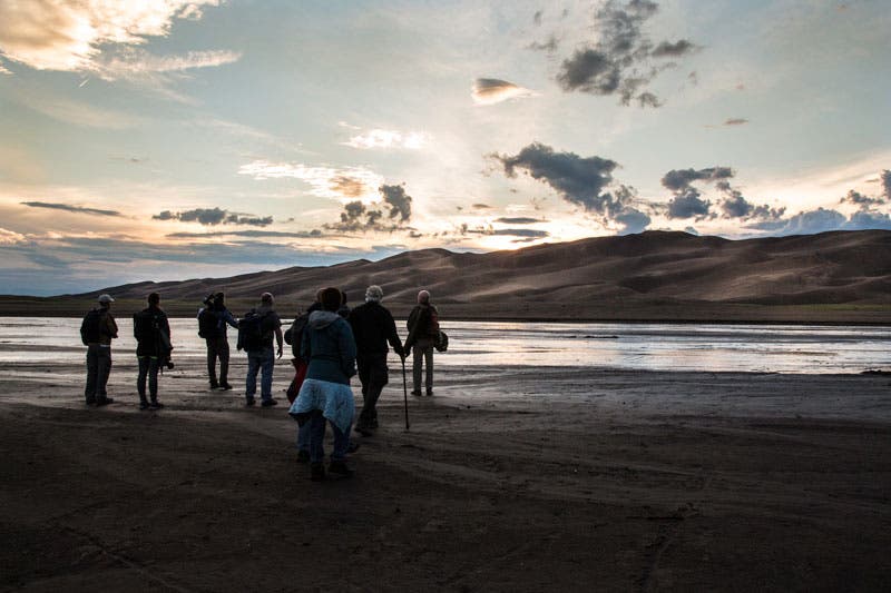 GreatSandDunes-NightSkies01_LinseyDodaro_800 Photographers attending the night skies workshop at Great Sand Dunes National Park cross Medano Creek on their way to the dune.