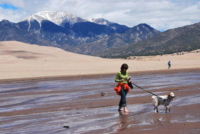 GreatSandDunes-dog-leash_NPSPatrickMyers_700 A woman with her dog on a leash in Great Sand Dunes National Park