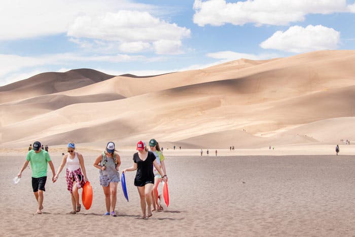Park visitors carrying sleds to the dunes at Great Sand Dunes National Park