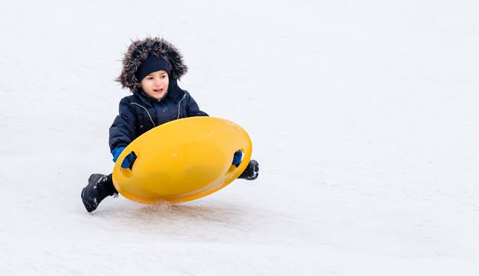 Child sledding with a snow saucer.