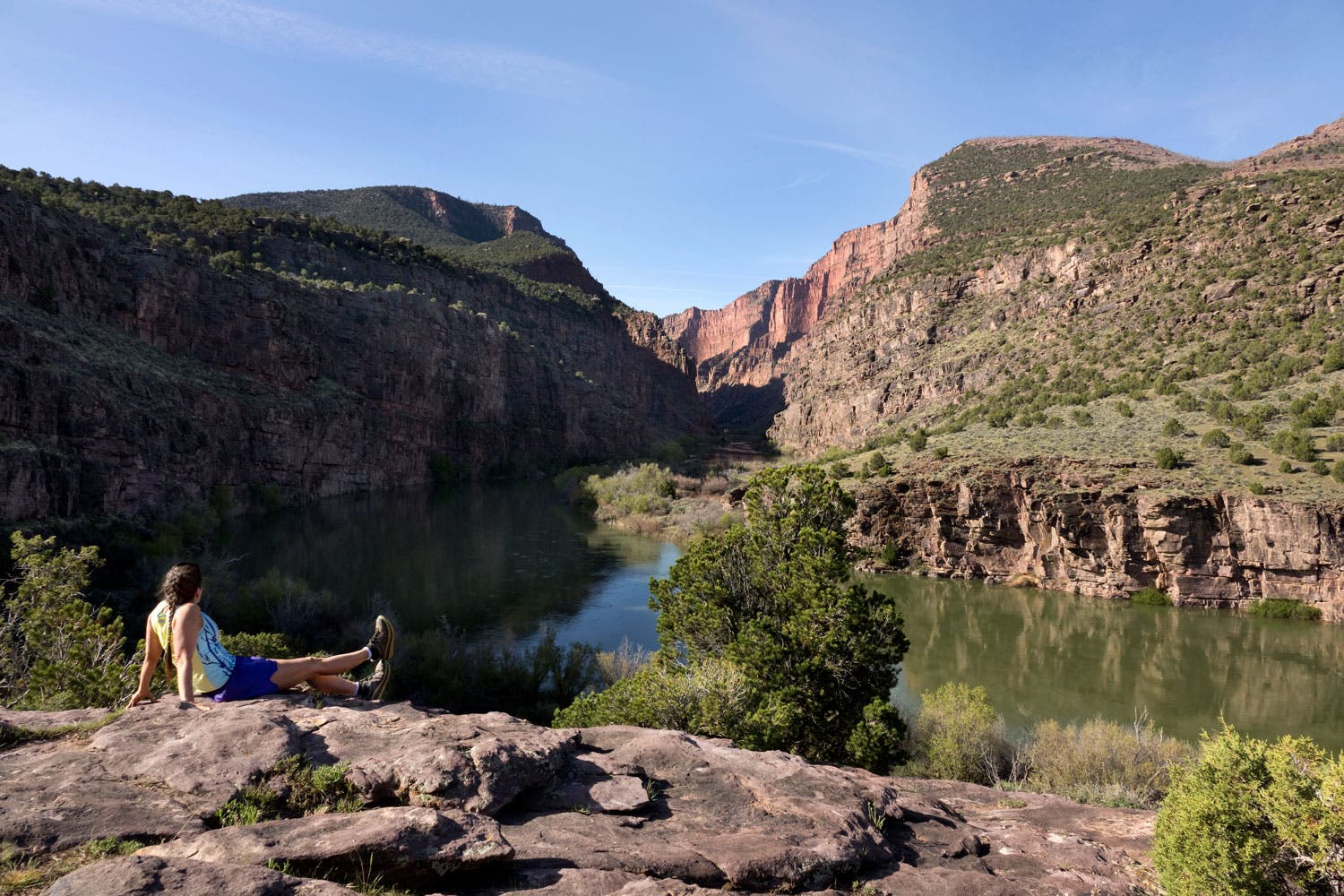 A hiker rests beside the Green River running through the Gates of Lodore in Dinosaur National Monument