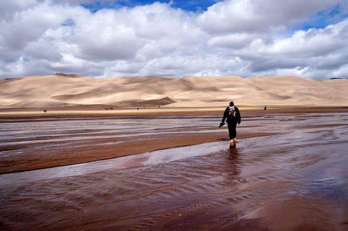 Great-Sand-Dunes-NP-Medano-Creek_Gloria_700 Hiker crosses Medano Creek in Great Sand Dunes National Park