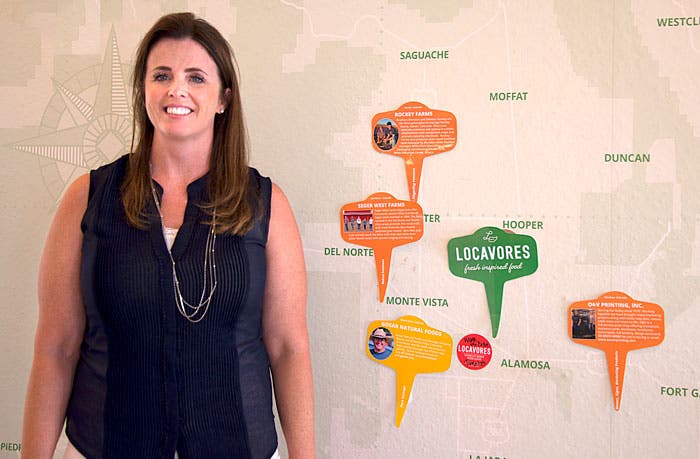 Owner Wendi Seger stands in front of a map showing farm supplier locations at Locavores in Alamosa, Colo.