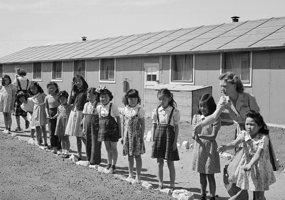 Elementary children landscaping the grounds in front of their barracks school at Amache in Colorado