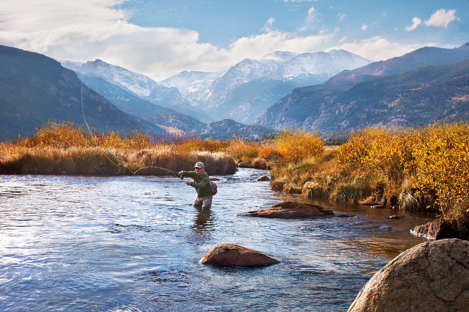 A man fly fishing against a backdrop of fall colors in Rocky Mountain National Park